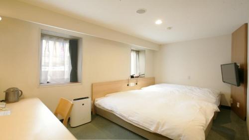 松本市にあるエースイン松本のベッドルーム(白いベッド1台、テレビ付)