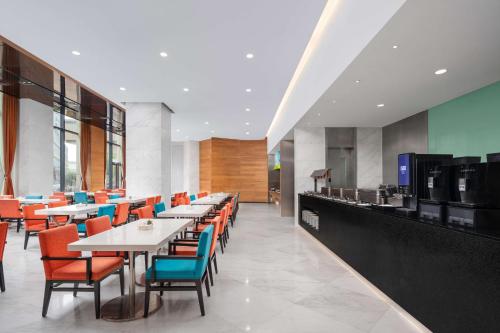 Holiday Inn Express Gulou Chengdu, an IHG Hotel في تشنغدو: غرفة طعام مع طاولات وكراسي ملونة