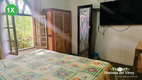 a bedroom with a bed and a flat screen tv at Hosteria Del Virrey - B&B in San Cristóbal de Las Casas
