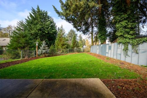 a yard with a fence and a grass field at Blue House - private 2 bed, 2 bath home with garage in Eugene