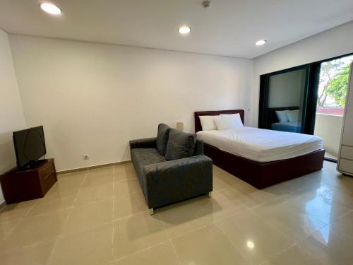a bedroom with a bed and a chair and a television at Ilha Flats in Luanda Beach in Luanda