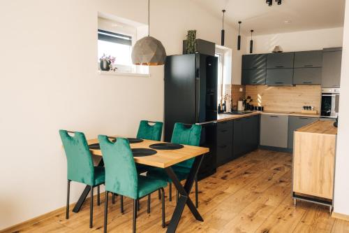 a kitchen with a wooden table and green chairs at Apartmány Na Vŕšku in Kežmarok