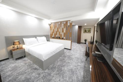 um quarto com uma cama e uma televisão de ecrã plano em Al jadriya Palace em Al Karrādah