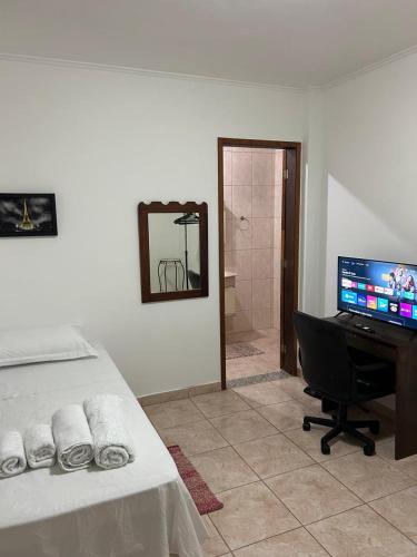 um quarto com uma cama e uma secretária com um computador em Quarto para solteiro(a). em São José dos Campos