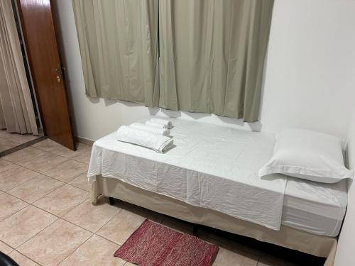 uma cama com lençóis brancos e almofadas num quarto em Quarto para solteiro(a). em São José dos Campos