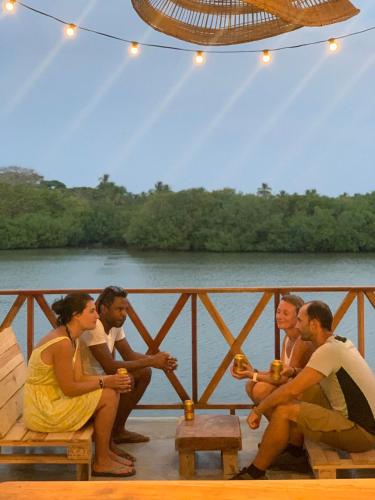a group of people sitting on a bridge near a river at Hostal Casa en la Ciénaga Rincon del Mar in Rincón