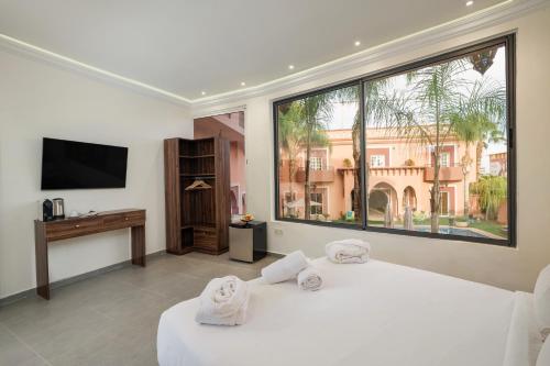 1 dormitorio con 2 camas blancas y ventana grande en Albakech Boutique Hôtel & Spa, en Marrakech