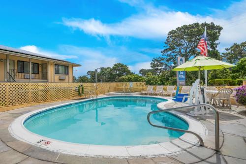 a swimming pool with an umbrella and chairs at Best Western Park Crest Inn in Monterey