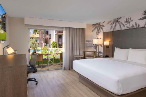 Best Western Plus Pepper Tree Inn في سانتا باربرا: غرفة في الفندق بسرير ومكتب وطاولة