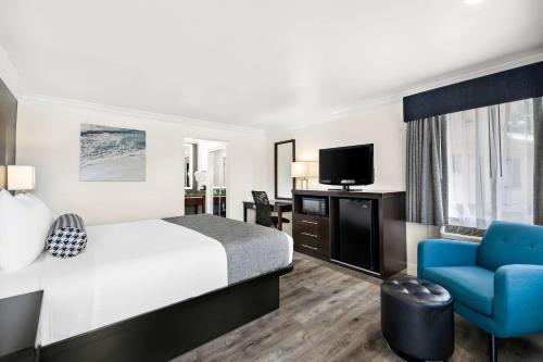 a hotel room with a bed and a blue chair at Best Western Park Crest Inn in Monterey