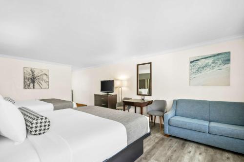 a hotel room with two beds and a blue couch at Best Western Park Crest Inn in Monterey