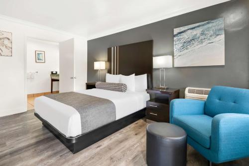 um quarto de hotel com uma cama e uma cadeira azul em Best Western Park Crest Inn em Monterey