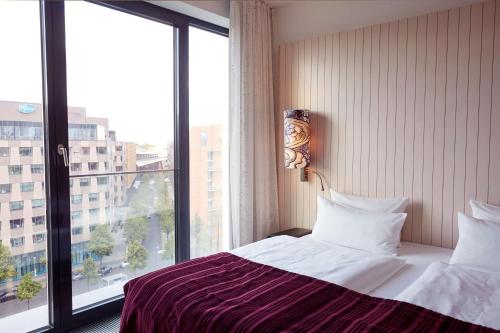 a hotel room with a bed and a large window at Scandic Berlin Potsdamer Platz in Berlin