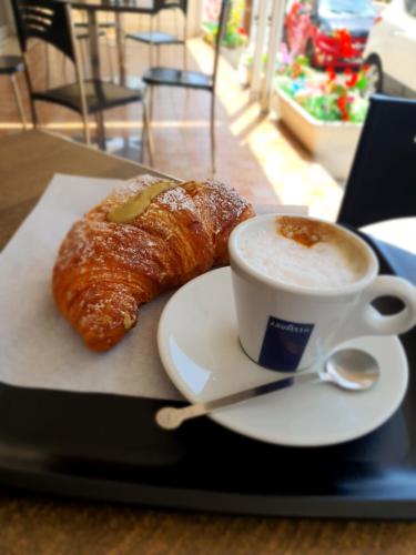 een kopje koffie en een croissant op een dienblad bij La barchetta in Gela