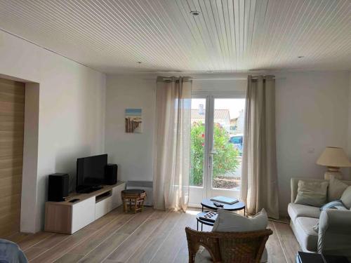 ein Wohnzimmer mit Sofa und Fernseher in der Unterkunft Maison 3 chambres Longeville in Longeville-sur-Mer