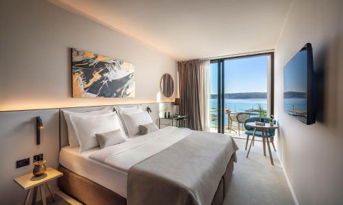 a hotel room with a large bed and a balcony at Aminess Younique Narrivi Hotel in Crikvenica