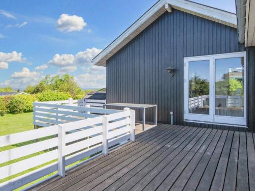 a wooden deck with a white fence and a house at 6 person holiday home in Glesborg in Glesborg