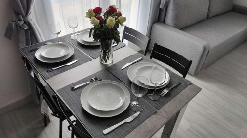 a table with plates and glasses and a vase of flowers at Chambre privée pour 4 personnes en banlieue parisienne à Bondy in Bondy