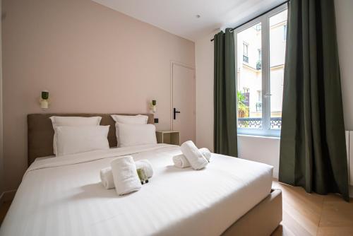 une chambre avec un grand lit blanc avec des serviettes dessus dans l'établissement Stylish Flat marais, à Paris