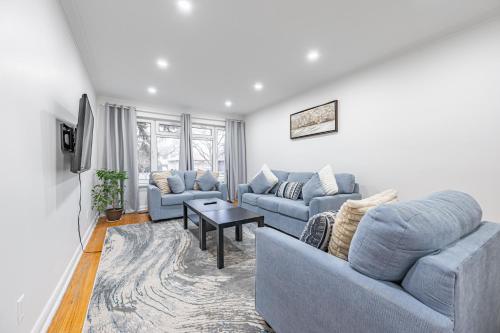una sala de estar con 2 sofás azules y una mesa. en Littlewood Properties en Toronto