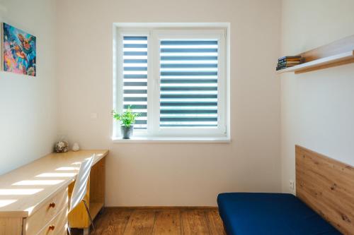 a bedroom with a window and a blue bench at Apartmány Na Vŕšku in Kežmarok