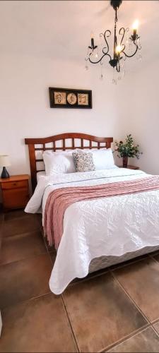 a bedroom with a bed with white sheets and a chandelier at Cabañas Toto Península Beach in Totoralillo