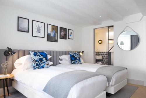 a bedroom with a large white bed with blue pillows at Kimpton De Witt Amsterdam by IHG in Amsterdam