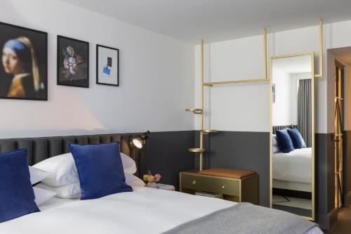 a bedroom with two beds and a mirror at Kimpton De Witt Amsterdam by IHG in Amsterdam