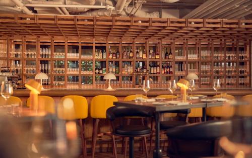 a restaurant with a bar with tables and yellow chairs at Kimpton De Witt Amsterdam by IHG in Amsterdam