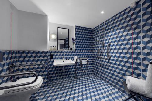 a blue and white bathroom with a sink and a toilet at Kimpton De Witt Amsterdam by IHG in Amsterdam