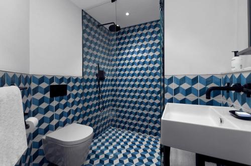 a bathroom with a toilet and a sink and blue and white tiles at Kimpton De Witt Amsterdam by IHG in Amsterdam