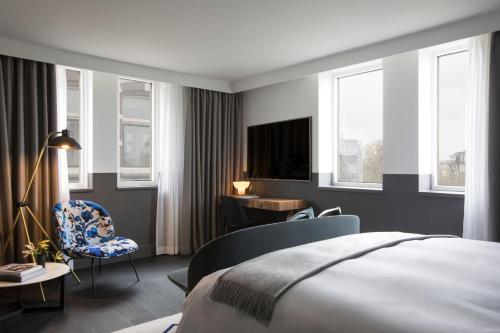 a bedroom with a bed and a desk and a tv at Kimpton De Witt Amsterdam by IHG in Amsterdam