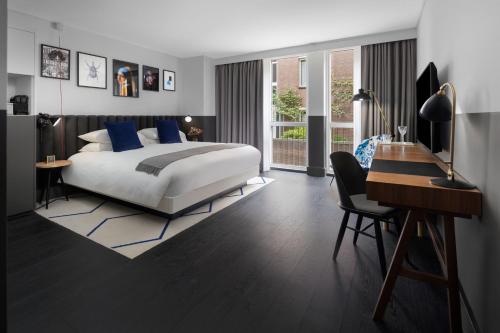 a bedroom with a large bed and a desk and a desk at Kimpton De Witt Amsterdam by IHG in Amsterdam