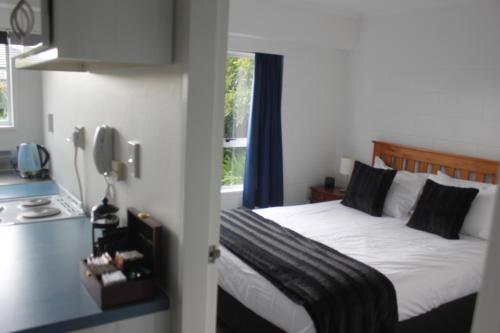 1 dormitorio con 1 cama con sábanas blancas y ventana en Kapiti Gateway Motel en Waikanae