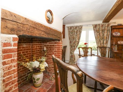 a living room with a brick fireplace and a wooden table at Lyons Green in Great Fransham