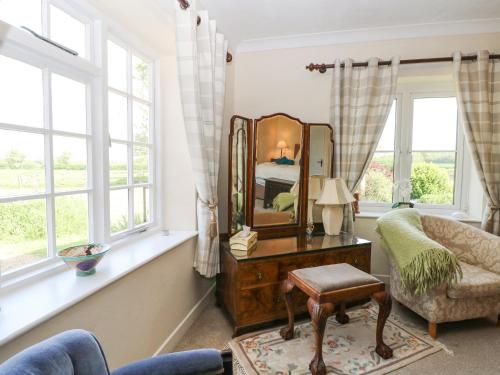 a living room with a mirror and a chair at Lyons Green in Great Fransham