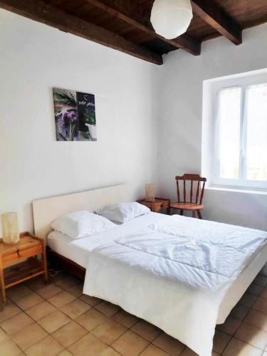 une chambre avec un lit blanc et une fenêtre dans l'établissement Gite 4/6p aux Portes du Périgord, à Castillonnès