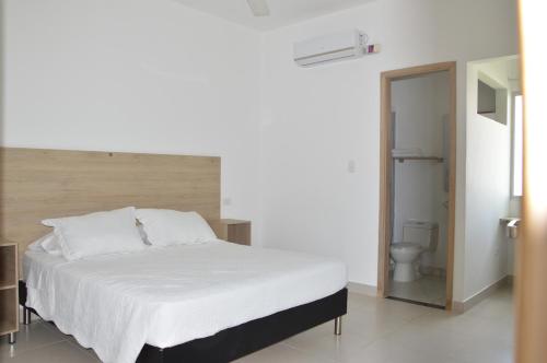 1 dormitorio con cama blanca y aseo en Hotel Ranchería Campestre, en Sahagún