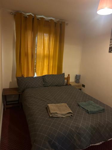 a bedroom with a bed with a yellow curtain at Lovely Woodford one bedroom apartment in London