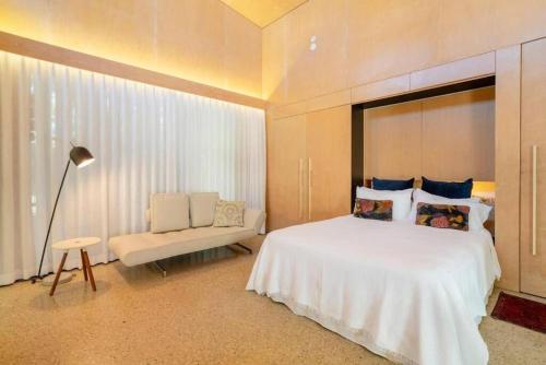 a bedroom with a large white bed and a chair at Buhwi Bira Byron Bay - Studio in Byron Bay