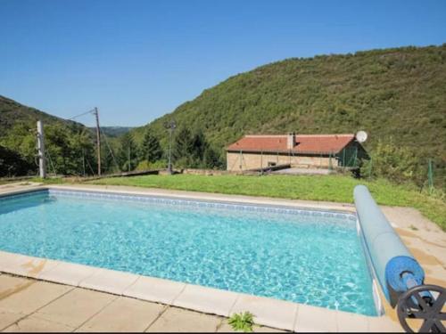 une piscine avec une maison en arrière-plan dans l'établissement Gite Brousse le Chateau, à Montclar