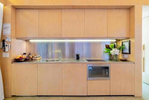 a kitchen with a sink and a microwave at Buhwi Bira Byron Bay - Studio in Byron Bay