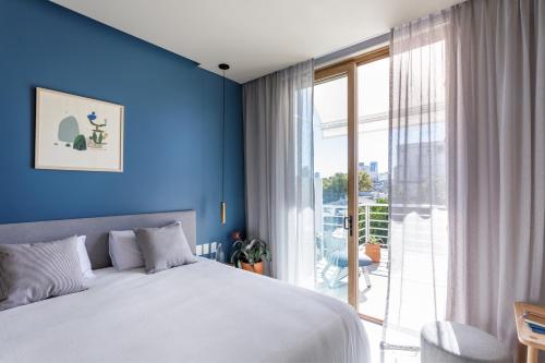 Dormitorio azul con cama y ventana grande en Bromelia Hotel Boutique en Buenos Aires