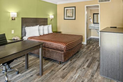 Habitación de hotel con cama y escritorio en Vagabond Inn Costa Mesa en Costa Mesa