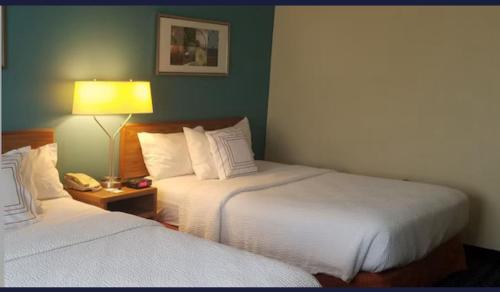 a hotel room with two beds and a lamp at AmericInn by Wyndham Moline Airport/Quad Cities in Moline