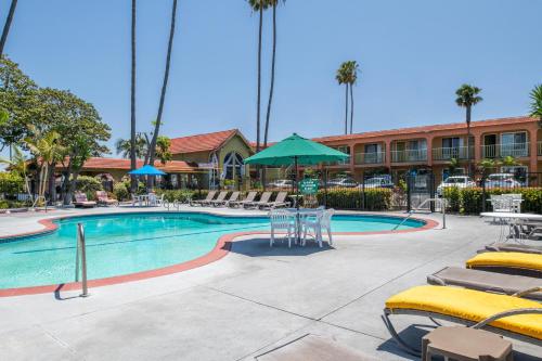 a pool with chairs and tables and a hotel at Vagabond Inn Costa Mesa in Costa Mesa