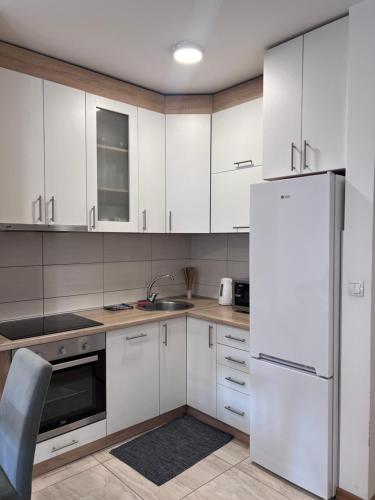 a kitchen with white cabinets and a refrigerator at MSCondoApartment in Kragujevac
