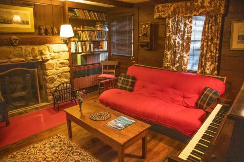 ein Wohnzimmer mit einem roten Sofa und einem Kamin in der Unterkunft Historic 1850s Home at the Base of Jump Mountain Near Lexington in Goshen