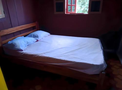 a bed with white sheets and a window in a room at Casas Salomão in Santo António