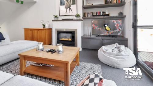 a living room with a coffee table and a fireplace at Snowbound Chalet 5 in Thredbo